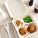 A Footprint Bagasse take-out box with food inside on a white background.