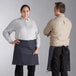 A man and woman wearing Acopa blue denim half bistro aprons with black webbing.