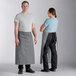 A man and woman wearing Acopa Kennett grey bistro aprons.