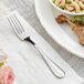An Acopa Brigitte stainless steel dinner fork on a plate with food.