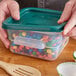 A hand holding a Vigor translucent square polypropylene food storage container filled with colorful candy.