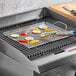 A stainless steel Outset grill tray with grilled vegetables on it.