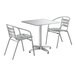 A white metal Lancaster Table & Seating outdoor table with two chairs.