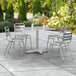 A Lancaster Table & Seating chrome square outdoor table with four silver chairs on a patio.