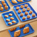 Baker's Mark light blue aluminum trays with pastries on a table.
