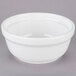 A Tuxton white china casserole bowl with a lid on a gray surface.