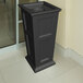 A black rectangular Mayne Fairfield decorative waste bin with a hole in the middle on an outdoor patio.