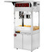 A Cretors floor model popcorn machine with popcorn in it.