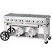 A large stainless steel Crown Verity outdoor grill with two white cylinders on a cart.