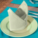 A folded seafoam green Intedge cloth napkin on a plate.