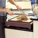 A person using a Cal-Mil Westport Carving Station to cut meat on a cutting board.