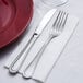 A fork and knife on a white Hoffmaster linen-feel dinner napkin.