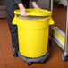 A woman putting a yellow Mobile Ingredient Storage Bin with a lid full of grains.