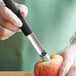 A hand using a Mercer Culinary apple corer to cut an apple.