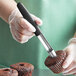 A person using a Mercer Culinary apple corer to cut out the center of a chocolate cupcake.