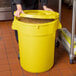 A woman holding a yellow round ingredient storage bin full of corn.