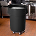 A person putting a large black Mobile Ingredient Storage Bin in a kitchen.