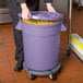 A woman holding a purple mobile ingredient storage bin full of pasta.