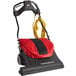 A red and black Sanitaire wide area vacuum cleaner with a bag and a handle.