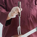 A person holding a Mercer Culinary Praxis® carving/pot fork with a rosewood handle.