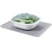 An OXO silicone drying mat with a white square container and a glass bowl of vegetables.