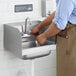 A person using a Steelton wall mounted hand sink with a gooseneck faucet to wash their hands.