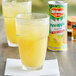 A glass of yellow liquid next to a can of Del Monte Pineapple Juice.