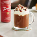 A glass mug of hot chocolate with whipped cream and Torani Chocolate Hazelnut Sauce.