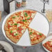 A pizza on a Choice aluminum coupe pizza pan with a slice missing.