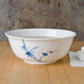 A close-up of a Thunder Group Blue Bamboo melamine bowl with a white swirl design in a bowl of liquid.