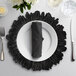 A 10 Strawberry Street black glass charger plate on a table set with a black place mat, napkin, and silverware.