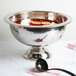 An American Metalcraft silver hammered punch bowl with a black ladle.