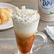 A glass cup of coffee with Reddi-Wip Coconut Milk Whipped Topping and a croissant.