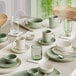 A table set with white Acopa Pangea sage matte porcelain cups on saucers.