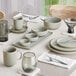 A table set with Acopa Pangea white porcelain bowls, plates, and cups.