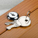 A key on a key ring unlocking an oak finish bulletin board cabinet.