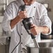A chef in a white coat using a Waring Big Stik immersion blender to make a sauce.