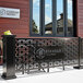 A black metal hexagonal partition panel on a table in an outdoor patio with a flower pot on the side.