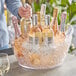 A group of bottles in a Choice large plastic oval wine bucket filled with ice.