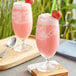 Two glasses of pink Fanale strawberry drinks with straws and strawberries on top.