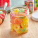 A clear plastic jar filled with colorful gummy candies.