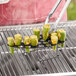 A Mr. Bar-B-Q jalapeno roaster holding green peppers on a grill.