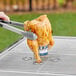 A chicken being cooked on a grill using a Mr. Bar-B-Q stainless steel beer can roaster.