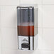 An Advance Tabco wall mount push button soap dispenser on a tile wall.