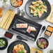 A table with Acopa Izumi matte black sauce dishes filled with food.
