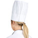 A woman wearing a white Chef Revival European chef hat.