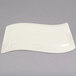 A Fineline Wavetrends ivory plastic rectangular plate with a curved edge.