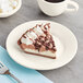 A piece of chocolate pie with whipped cream and chocolate chips on an Acopa ivory stoneware plate.
