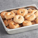 A metal pan filled with Original Bagel whole wheat mini bagels.