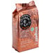 A brown Lavazza Tierra! Brasile whole bean coffee bag with a black and white label featuring a hand holding a seed.